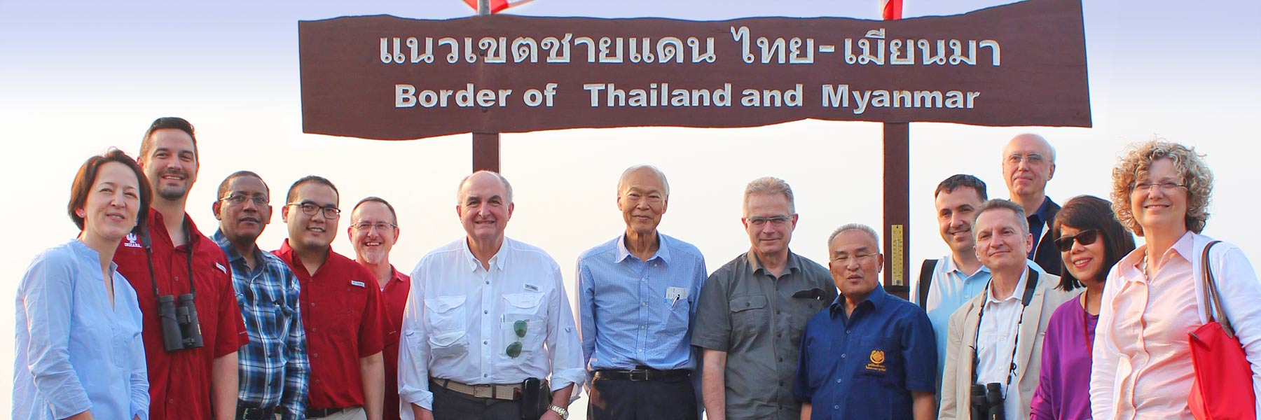 President McRobbie poses with a group at a sign marking the border of Thailand and Myanmar