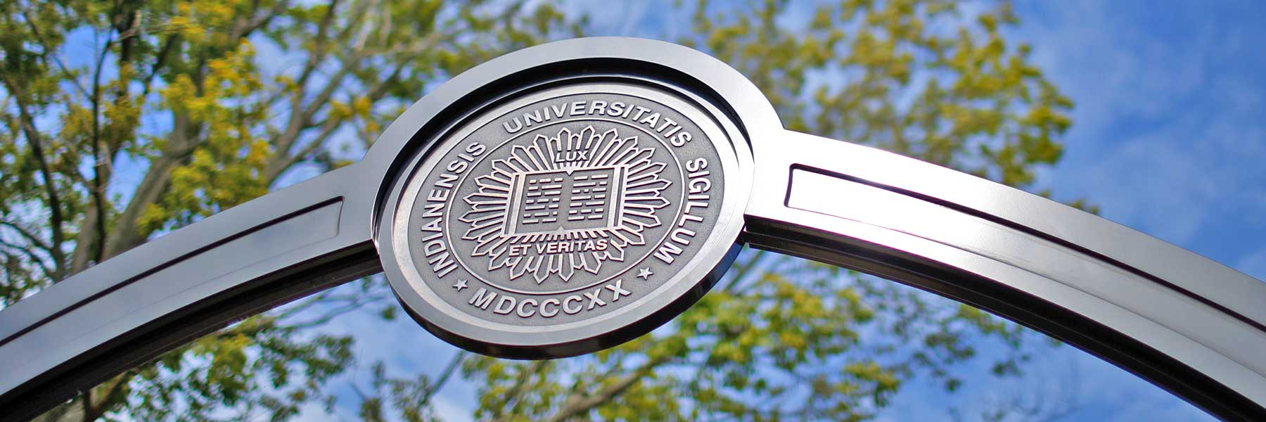 An IU seal crowns an arched gateway entrance to the Bloomington campus