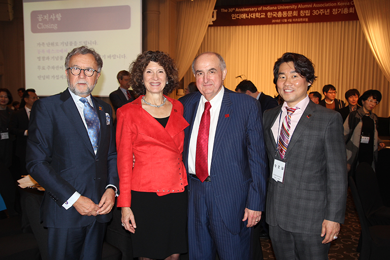 IU First Lady Laurie Burns McRobbie and IU President Michael A. McRobbie stand with two graduates...