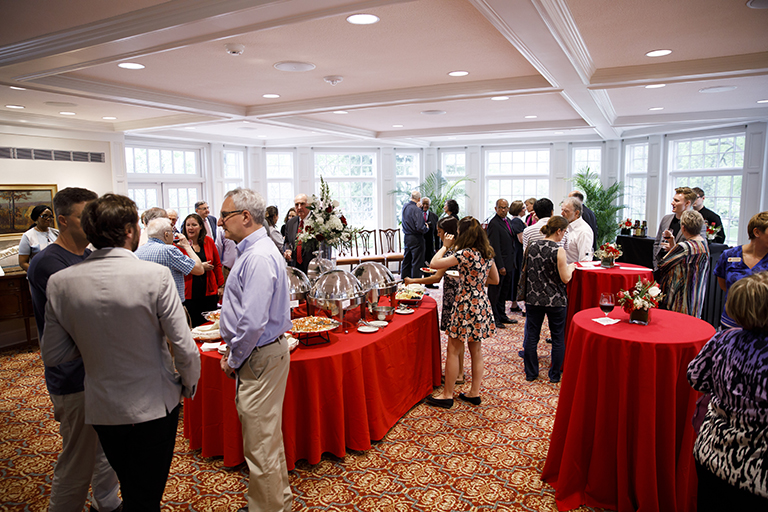 Faculty, staff and guests mingle in the Tobias Pavilion at Bryan House during a reception in hono...