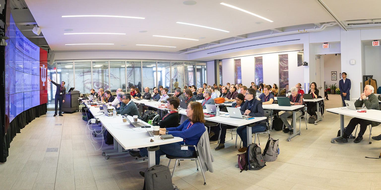 Manish Parashar points to a large screen in front of a group of about 75 people seated in a room