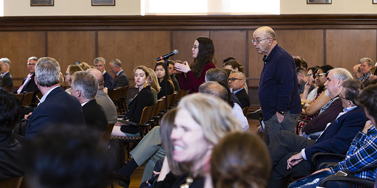 One person speaks into a microphone and another lines up behind her to speak next