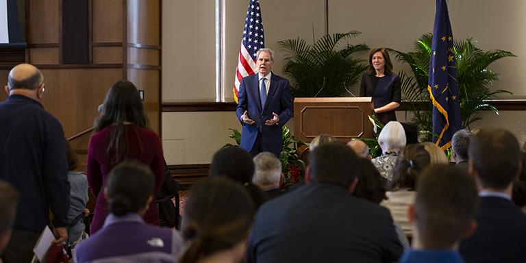 David Carden stands at the front of the room while talking to a member of the audience 