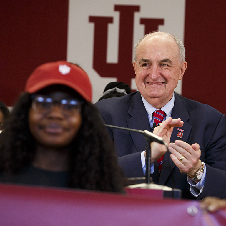 IU President McRobbie stands with a group of students and applauds 