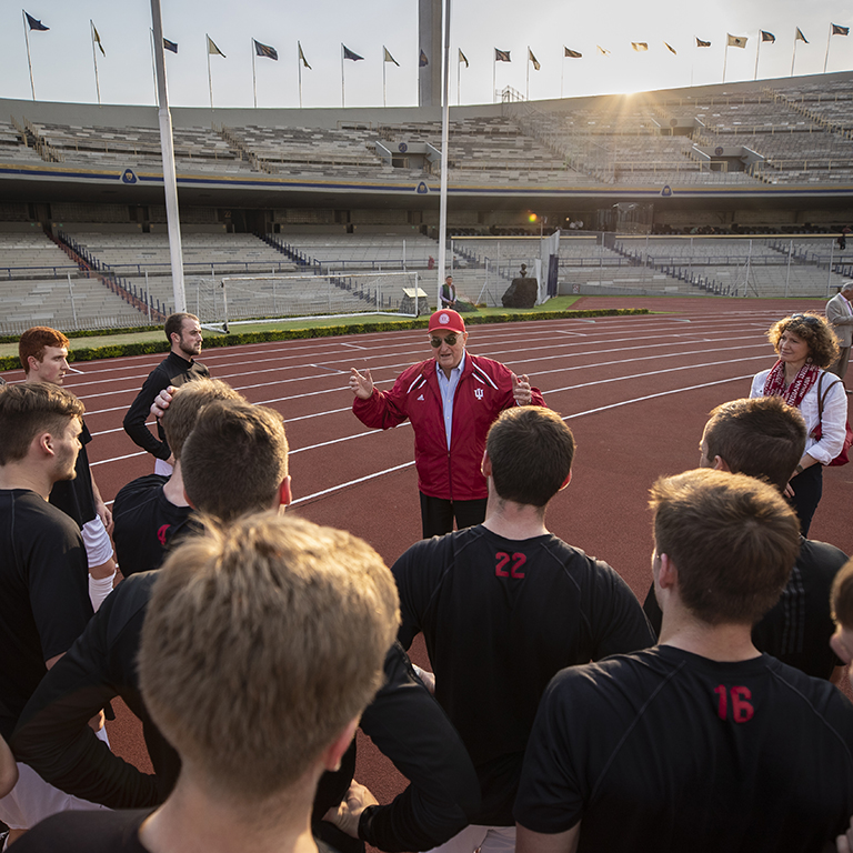 IU President McRobbie talks to members of the IU men's soccer team on a soccer field